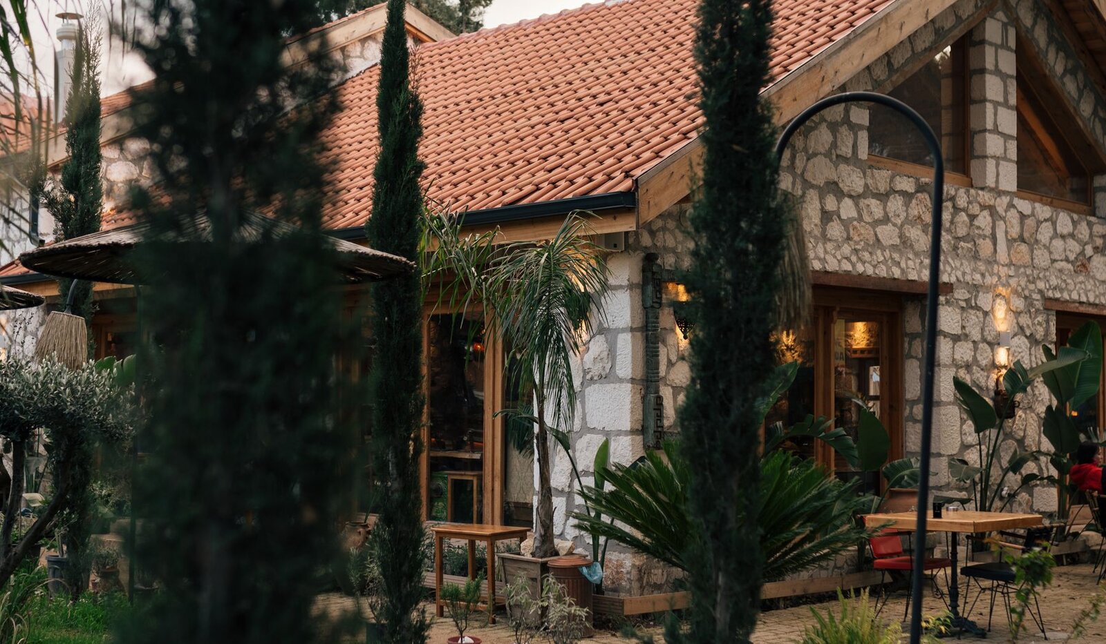 A stone house with a tiled roof surrounded by a leafy garden
